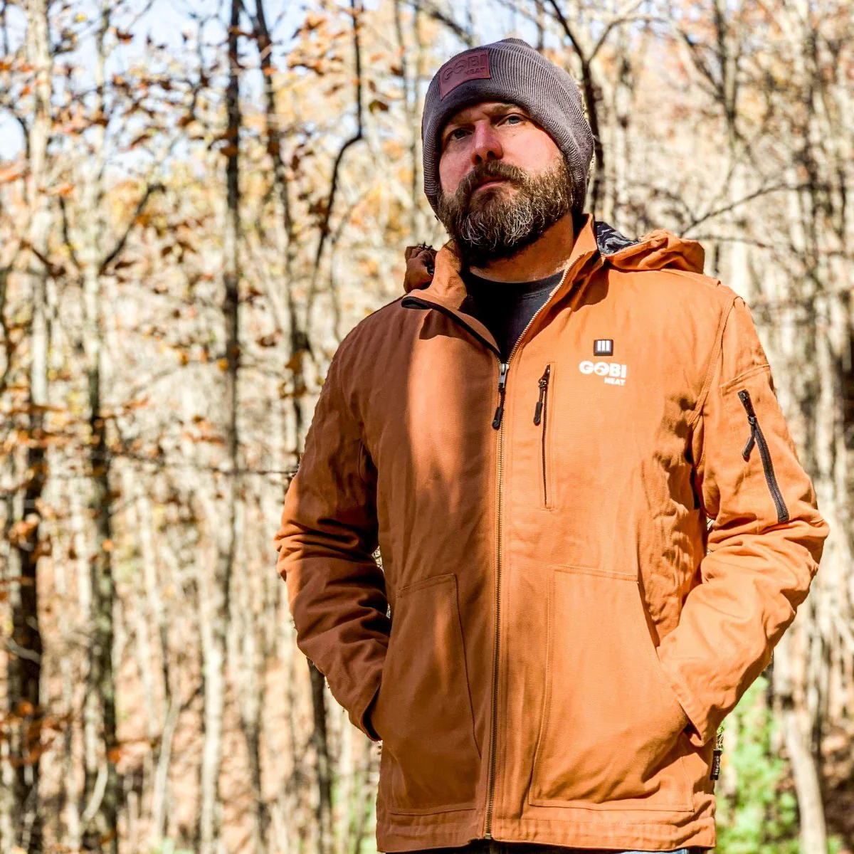 Man wearing the Gobi Heat Grit Heated Work Jacket in Grizzly color outdoors demonstrating rugged duck-cotton design